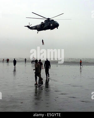 Karachi. 31. Juli 2014. Pakistan Marine Sea King Hubschrauber ist mit einem Froschmann, befestigt an einer Winde aus dem Flugzeug, die einen wiederhergestellten Körper ein ertrinkendes Opfer über Clifton Beach im südlichen Hafenstadt pakistanischen Stadt Karachi am 31. Juli 2014 transportiert gesehen. Mindestens 19 Leichen der Opfer wurden wiederhergestellt, nachdem sie beim Baden im Meer in der Nähe von Pakistans südlichen Hafen Stadt Karachi am Mittwoch, ertrunken war, berichteten lokale Medien. © Arshad/Xinhua/Alamy Live-Nachrichten Stockfoto