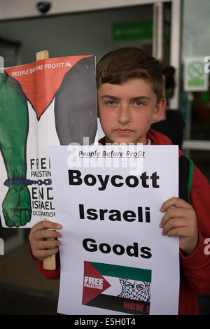 Andersonstown Rd, West Belfast, Irland. 31. Juli 2014. Ein Junge hält ein "Boykott Isralei waren" Plakat außerhalb ASDA Supermarkt. Der Protest war die Leute zu Boykott Kauf israelische waren wegen des aktuellen Konflikts in Gaza Kredit Fragen: Bonzo/Alamy Live News Stockfoto