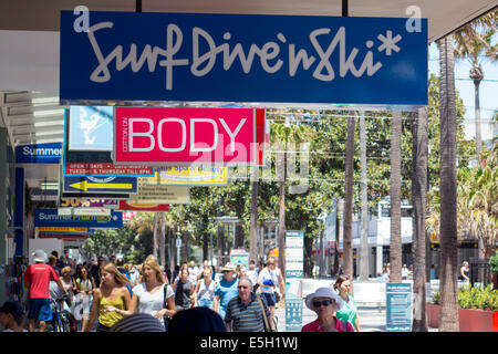 Menschen beim Einkaufen auf dem Corso, der Haupteinkaufsstraße in Manly, mit typischen Beschilderung (Baumwolle auf Körper, Dive & Surfski) für outd Stockfoto