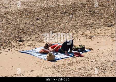 Junge Frau schlief in der Sonne am Strand von Whitstable Kent England UK Stockfoto