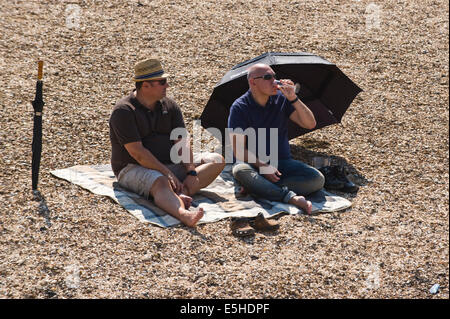 Zwei Männer mittleren Alters zum Entspannen in der Sonne am Strand während der jährlichen Oyster Festival in Whitstable Kent England UK Stockfoto