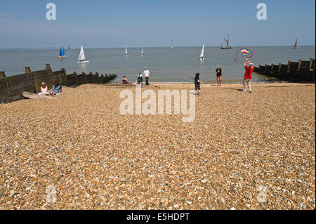 Menschen in der Sonne am Strand relaxen & spielen mit Kite bei Whitstable Kent England UK Stockfoto