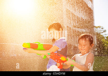 Fröhliche Mädchen spielen Wasserpistolen im park Stockfoto