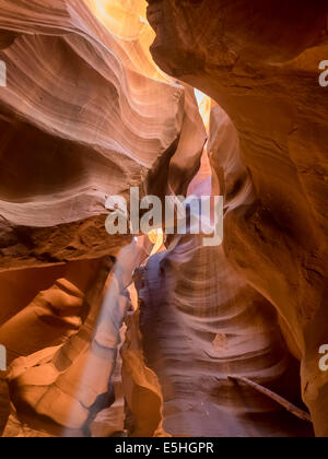 Mittag in einem rot-Orange Antelope Canyon. Ein dünner Strahl des Tageslichtes leuchtet auf dem sandigen Boden des Canyons Stockfoto