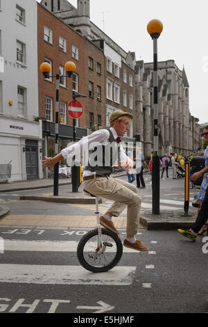 A Street Performer auf einem Einrad unterhalten das Publikum in Marylebone Street Sommer Fayre fair, London, UK. Stockfoto