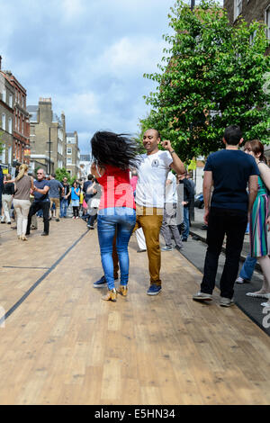 Ein attraktives junges Paartanz auf einer hölzernen Tanzfläche auf der Marylebone Sommer Street Fayre fair Party, London, UK. Stockfoto