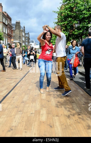 Ein paar tanzt auf einem hölzernen Dancefloor in der Öffentlichkeit bei der Marylebone Street Sommer Fayre fair Party, London, UK. Stockfoto