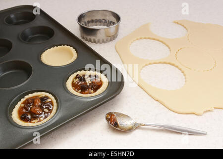 Herstellung von Mince Pies, Teig Kreise mit Cutter schneiden und mit Hackfleisch füllen Stockfoto