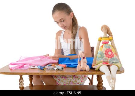 Das Mädchen näht Spielzeug aus Stoff auf dem weißen Hintergrund Stockfoto