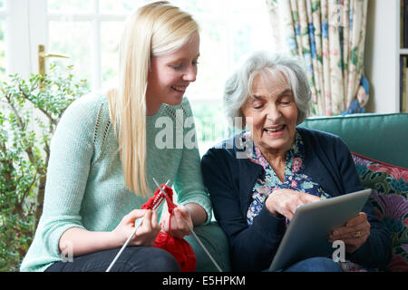 Großmutter mit Digital-Tablette als Enkelin strickt Stockfoto