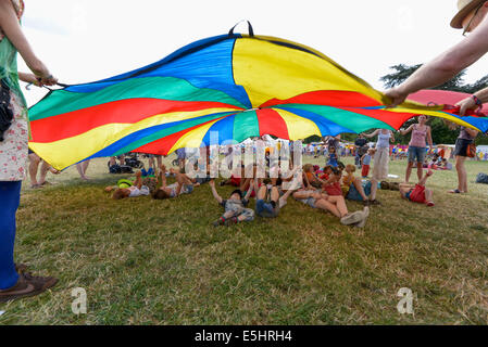 Malmesbury, Großbritannien, 27.07.2014: Atmosphäre bei WOMAD - Welt der Musik, Kunst und Tanz. Chlidrens Spiele unter einem großen Fallschirm im Kids-Bereich. Bild von Julie Edwards Stockfoto