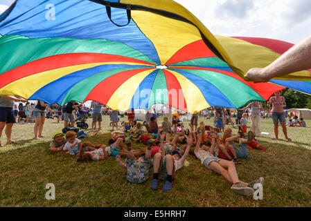 Malmesbury, Großbritannien, 27.07.2014: Atmosphäre bei WOMAD - Welt der Musik, Kunst und Tanz. Chlidrens Spiele unter einem großen Fallschirm im Kids-Bereich. Bild von Julie Edwards Stockfoto