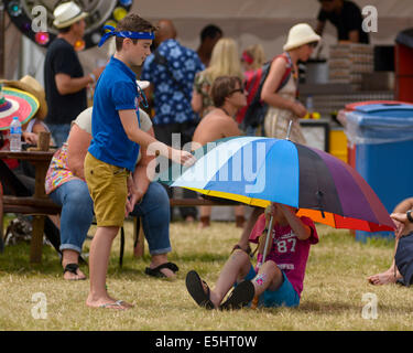 Malmesbury, Großbritannien, 27.07.2014: 2 Jungen spielen mit einem bunten Regenschirm bei WOMAD - World of Music, Arts and Dance. Bild von Julie Edwards Stockfoto