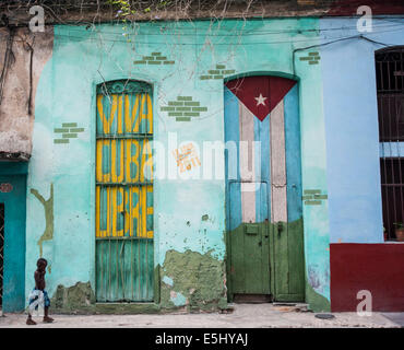 Kind geht vorbei an Wandbild auf Gebäude mit der Aufschrift Viva Cuba Libre in Havanna, Kuba Stockfoto