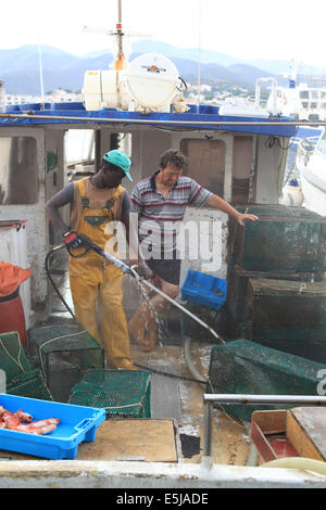 Fischer Schlauch nach unten die Netze nach eines Tages Angeln, beobachtet von einem anderen Besatzungsmitglied im Fischereihafen Llanca, Costa Brava, Spanien. Stockfoto