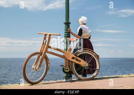 Niederlande, Urk, Ast Bike. Das Dutch Design aus Holz-Bike ist eine Schöpfung von Jan Gunneweg. Mädchen in Tracht Sonntag Stockfoto