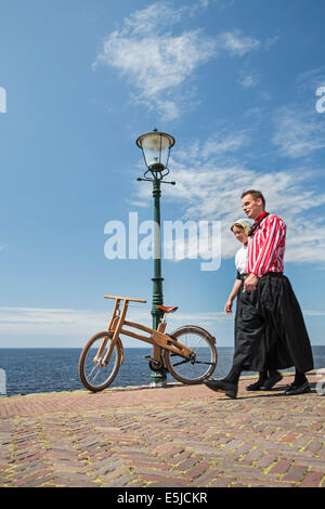 Niederlande, Urk, Ast Bike. Das Dutch Design Holz Bike, Erstellung von Jan Gunneweg. Mann und Frau in Tracht Sonntag Stockfoto