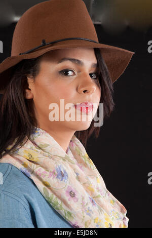 Ziemlich langhaarige Brünette Frau in braune Hut, stehend mit einem plädierte aber nachdenklichen Ausdruck Stockfoto