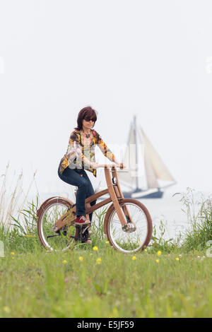 Niederlande, Venhuizen, Frau Ast Fahrrad. Das Dutch Design aus Holz-Bike ist eine Schöpfung von Jan Gunneweg. Segelboot Stockfoto