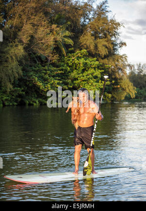 Kauai Bewohner mit seinem Hund am Hanalei River; Hund begleitet Eigentümer, wenn er geht, stand up Paddle Surfen in Hanalei Bay Stockfoto