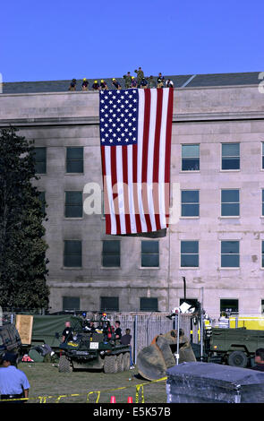 Feuerwehrleute und Soldaten entfalten die amerikanische Flagge entlang der Fassade des Pentagons in der Nähe der Absturzstelle durch folgende Terroranschläge 12. September 2001 in Arlington, VA. Stockfoto