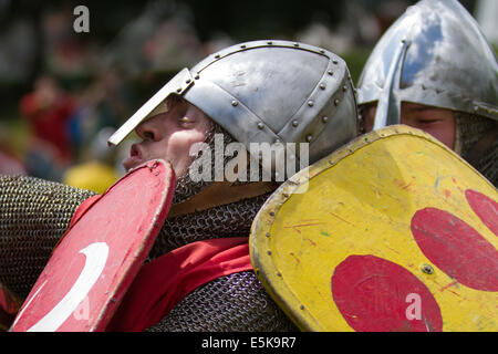 Beeston Castle, Cheshire, Großbritannien, 3. August 2014. Helmetrische bewaffnete Re-Enactors mit Schilden, beim Medieval Knights Tournament and Melee, einem Foot Soldier Combat Event. Historia Normannis, eine frühmittelalterlichen Kampfreenactment-Gruppe aus dem 12. Jahrhundert, erklärt die alte Kultur und Bräuche und stellt Ketten- und adrenalinbetriebene Reenactor Teams hochqualifizierter Ritter zur Verfügung, um mit Schwert-, Schild- und Vereinswaffen frontal zu kämpfen - eine Veranstaltung auf der English Heritage Site. Stockfoto