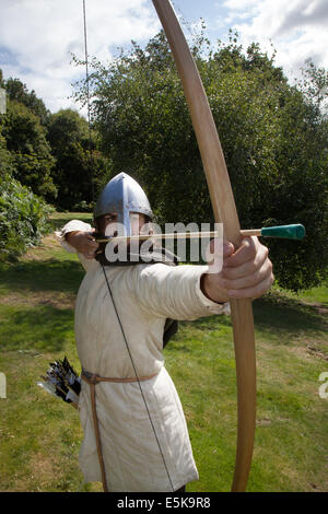 Archer zielt auf Beeston, Keshire, Großbritannien 3.. August 2014. Dominic Tucker ein englischer Langbogen-Bogenschütze mit D-Bogen beim Medieval Knights Tournament, das auf Beeston Castle in der englischen Grafschaft cheshire stattfand. Historia Normannist eine frühmittelalterliche Nachschauungsgruppe aus dem 12.. Jahrhundert, Genauigkeit, Konzentrat, Kämpfer. bogenschütze, Langbogen, Bogen, Bogenschießen, Pfeil, Waffe, Ziel, Ziel, Sport, schießen, jagen, zielen, Präzision, Vektor, Turnierkämpfer, Ketten-geschickte und adrenalingeladene Teams aus hochqualifizierten bewaffneten Bogenschützen und englischen Rittern treffen sich direkt auf der English Heritage Site. Stockfoto