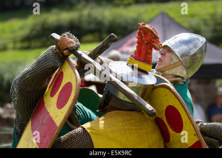 Beeston Castle, Cheshire, Großbritannien, 3. August 2014. Helmetrische bewaffnete Re-Enactors mit Schilden, beim Medieval Knights Tournament and Melee, einem Foot Soldier Combat Event. Historia Normannis, eine frühmittelalterlichen Kampfreenactment-Gruppe aus dem 12. Jahrhundert, erklärt die alte Kultur und Bräuche und stellt Ketten- und adrenalinbetriebene Reenactor Teams hochqualifizierter Ritter zur Verfügung, um mit Schwert-, Schild- und Vereinswaffen frontal zu kämpfen - eine Veranstaltung auf der English Heritage Site. Stockfoto