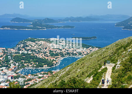 Zwei Wanderer auf dem Weg nach unten vom Berg Srd zur ummauerten Stadt Dubrovnik mit Blick auf den Hafen Gruz und Inseln jenseits Stockfoto