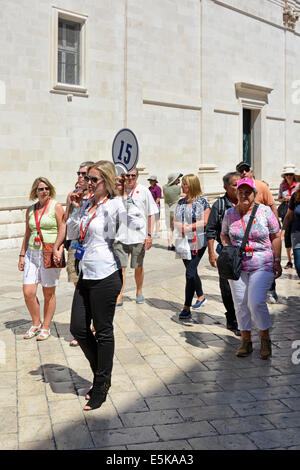 Reiseleiter hält die Flagge des Kreuzfahrtschiffes und spricht in Echtzeit in mike, um Audio mit ihrer Gruppe Dubrovnik Croatia Dalmatia Adriatic zu verbinden Stockfoto