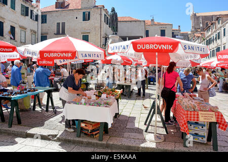 Stall und Sonnenschirme auf dem bunten historischen Marktplatz mit Stall Inhaber Touristen und Käufer Stadt Dubrovnik Kroatien Dalmatien Adria Europa Stockfoto