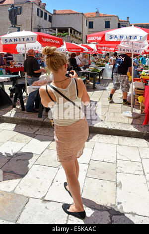 Rückansicht Frau Tourist Person Foto auf Handy machen beschäftigt bunten Marktplatz Stände & Sonnenschirm Dubrovnik Kroatien Dalmatien Adria Europa Stockfoto