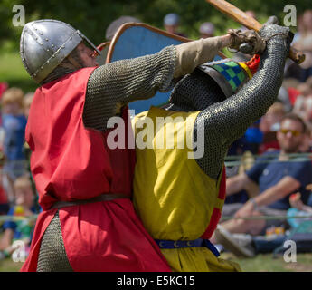 Beeston Castle, Cheshire, Großbritannien, 3. August 2014. Helmetrische bewaffnete Re-Enactors mit Schilden, beim Medieval Knights Tournament and Melee, einem Foot Soldier Combat Event. Historia Normannis, eine frühmittelalterlichen Kampfreenactment-Gruppe aus dem 12. Jahrhundert, erklärt die alte Kultur und Bräuche und stellt Ketten- und adrenalinbetriebene Reenactor Teams hochqualifizierter Ritter zur Verfügung, um mit Schwert-, Schild- und Vereinswaffen frontal zu kämpfen - eine Veranstaltung auf der English Heritage Site. Stockfoto