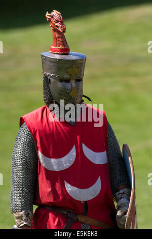 Beeston, Cheshire, UK 3. August 2014. Dunkle Visored Barbuta Helm Rüstung, Behelmte bewaffneten re-Enactor mit Schild, am mittelalterlichen gepanzerte Ritter, Verteidigung gegen fliegende Pfeile, am Turnier in Beeston Castle in Cheshire, England. Historia Normannis ein 12. Jahrhundert frühes Mittelalter Reenactment Gruppe Kette - verschickt und Adrenalin-betriebene Teams von hochqualifizierten Rittern zu Met mit Schild und Club eine Veranstaltung auf dem English Heritage Site. Stockfoto