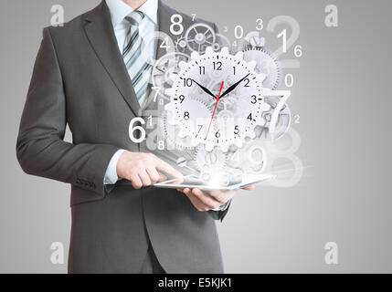 Geschäftsmann halten Tablet-pc mit Uhr und Zahnräder Stockfoto