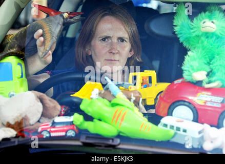 Gestresste Mutter überwältigt durch Berge von Kinder Spielzeug in ihrem Auto, guckt durch eine Lücke, durch die Windschutzscheibe sehen Stockfoto