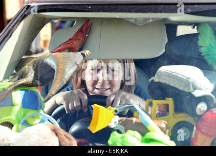 Gestresste Mutter überwältigt durch Berge von Kinder Spielzeug in ihrem Auto, guckt durch eine Lücke, durch die Windschutzscheibe sehen Stockfoto