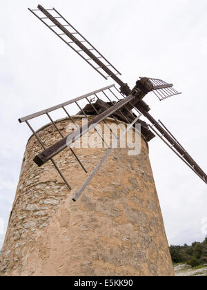 Alten ausgedienten Windmühle hoch über dem Dorf. Der steinerne Turm mit hölzernen Schaufeln verzogen und Split durch das Wetter. Stockfoto