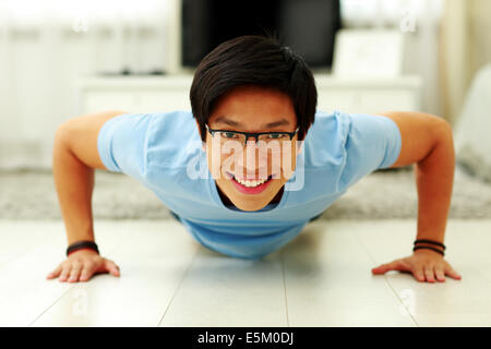 Porträt eines glücklichen jungen Mannes doing Push-Ups in das Wohnzimmer zu Hause Stockfoto