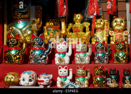 Nahaufnahme des sonnenbeleuchteten japanischen Maneki Neko, der Katzen in einem Schaufenster in Chinatown, Soho, London, England, Großbritannien winkt Stockfoto