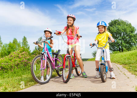 Drei Mädchen auf einem ebnen Weg mit Fahrrädern Stockfoto