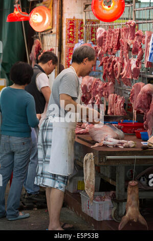 Hong Kong Metzger Schneiden von Fleisch an eine Gage Straßenmarkt. Stockfoto