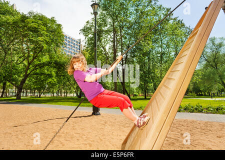 Mädchen Klettern auf Holzkonstruktion im park Stockfoto