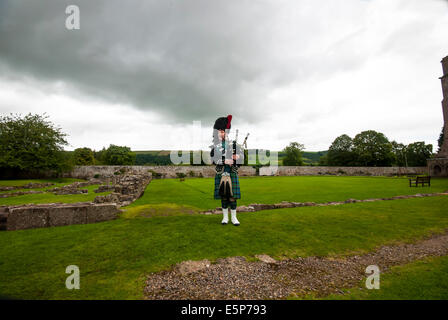 Eine einsame Piper spielt unter den Ruinen der Melrose Abbey in der schottischen Grenze Stadt Melrose Stockfoto