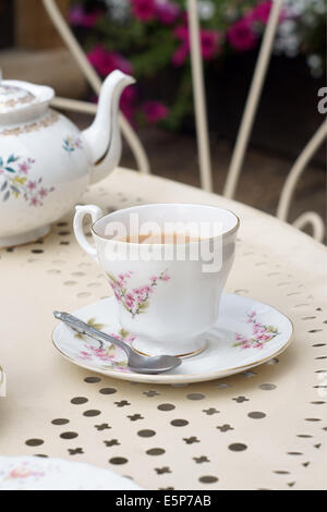 Nachmittagstee wird in Vintage-Blumentöpfen und Untertöpfen auf einem Gartentisch serviert Stockfoto