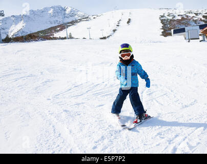 Junge im Ski-Maske lernt Skifahren auf Schnee bergab Stockfoto