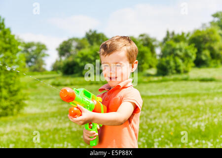 Kleiner Junge spielt mit einer Wasserpistole Stockfoto