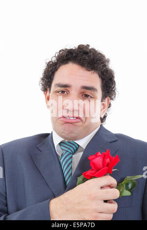 Erwachsenen sehr enttäuscht und traurig Mann im Anzug mit seltsamen geeky Gesichtsausdruck hielt mit seiner Hand rose Blume, die in seinem Stockfoto