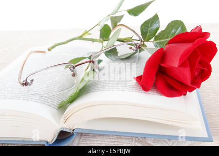 Aufgeschlagene Buch und die rote Rose mit Brille auf Seiten des Buches, Romantik-look Stockfoto