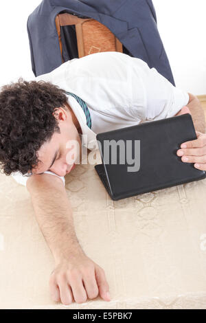 Foto von erschöpft, Schlaf- und überlasteten Geschäftsmann mit Laptop neben ihm am Schreibtisch bei seiner Arbeit Stockfoto